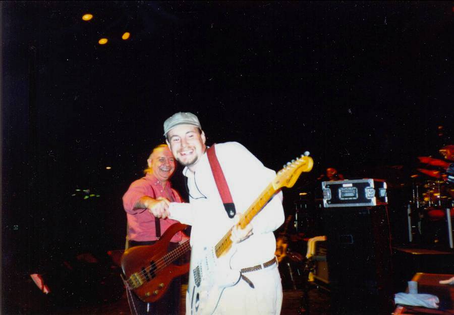 Tim Tye appearing onstage with The Guess Who shaking hands with bass player Jim Kale
